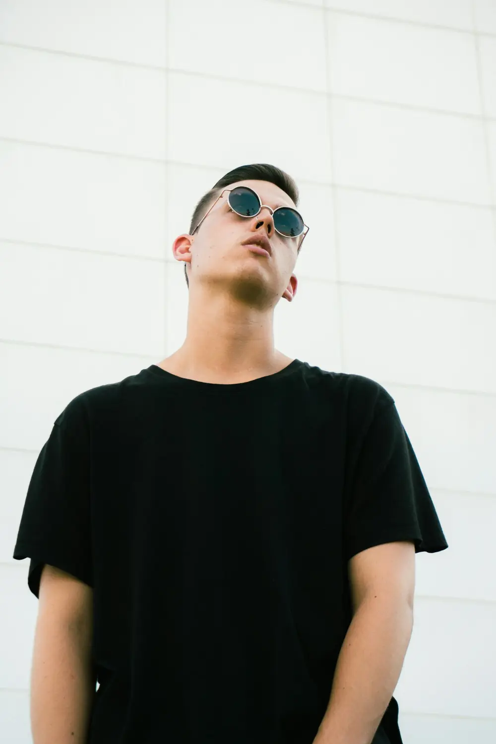 Man in a black oversized t-shirt and round sunglasses